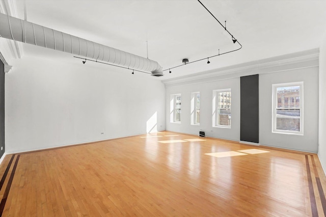 unfurnished living room featuring basketball court, light hardwood / wood-style flooring, and rail lighting