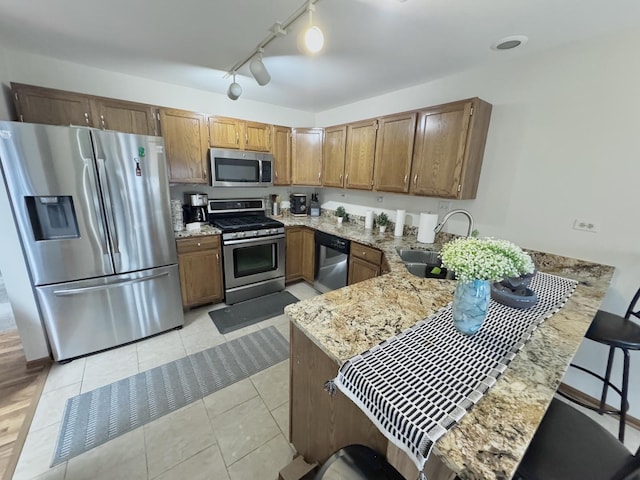 kitchen with a breakfast bar, stainless steel appliances, kitchen peninsula, and sink