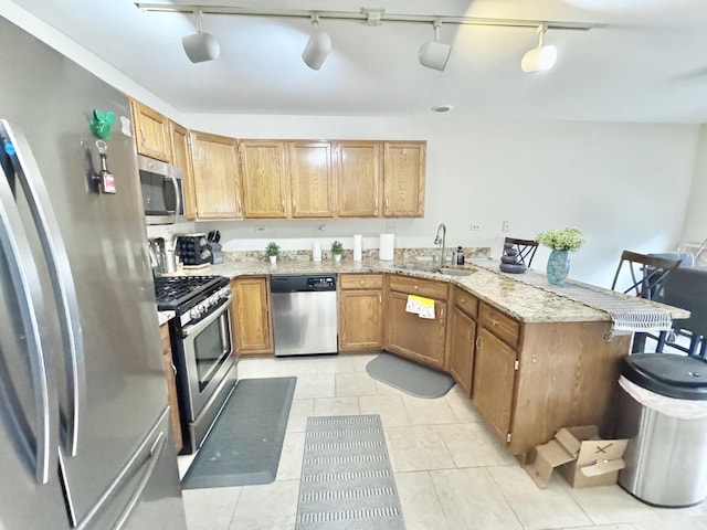 kitchen with sink, a kitchen bar, kitchen peninsula, stainless steel appliances, and light stone countertops