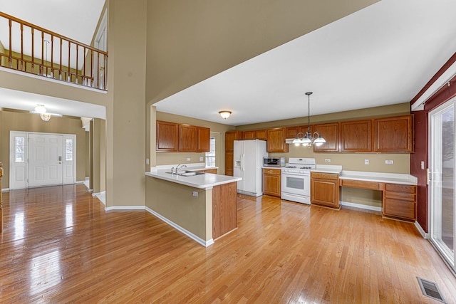 kitchen featuring white appliances, decorative light fixtures, kitchen peninsula, and light wood-type flooring