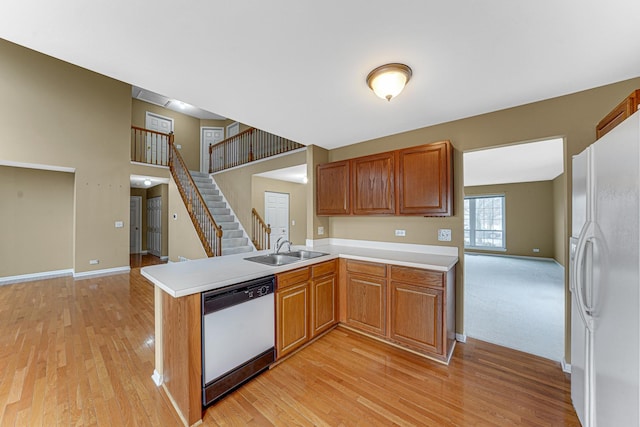 kitchen with sink, white refrigerator, stainless steel dishwasher, kitchen peninsula, and light hardwood / wood-style floors