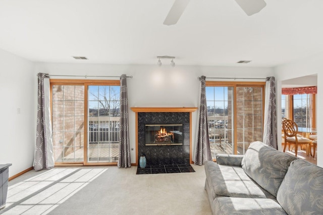 carpeted living room featuring ceiling fan and a fireplace