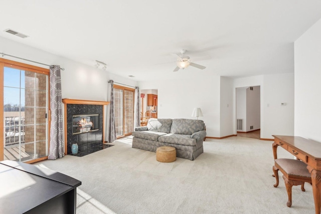 living room with a tile fireplace, rail lighting, carpet floors, and ceiling fan