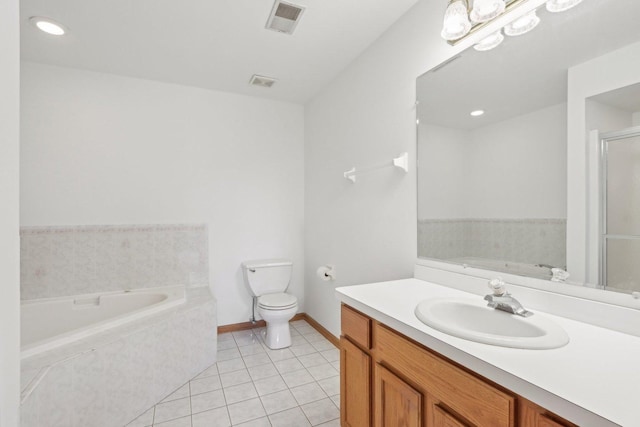 bathroom featuring vanity, a relaxing tiled tub, tile patterned floors, and toilet