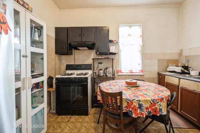 kitchen with light parquet flooring, dark brown cabinets, tile walls, and range with gas cooktop