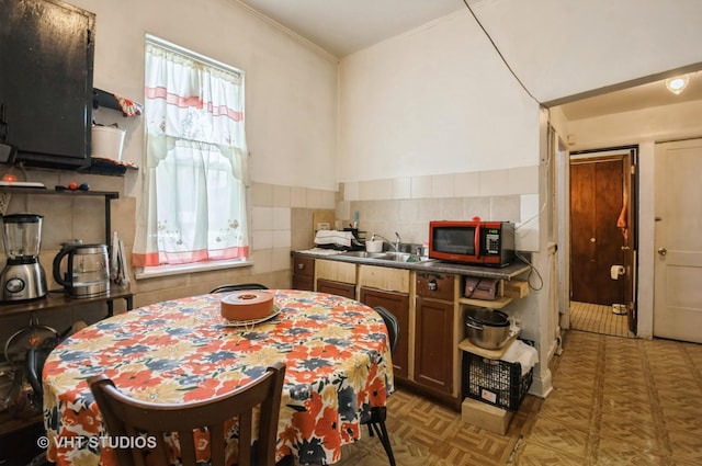 kitchen with ornamental molding, sink, tile walls, and dark parquet flooring