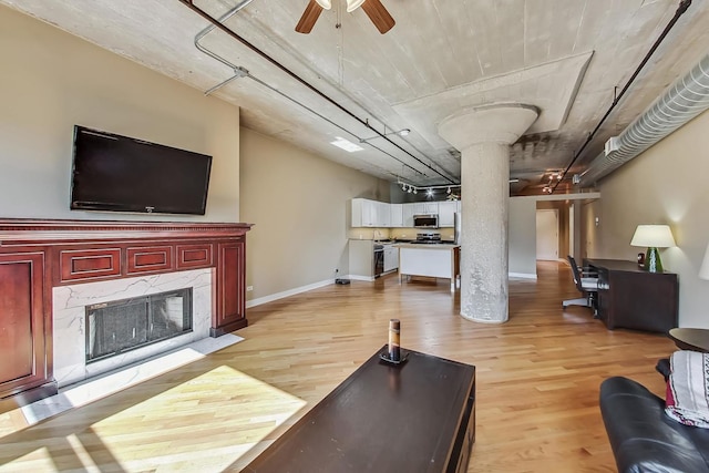 living room with ornate columns, ceiling fan, a high end fireplace, and light wood-type flooring