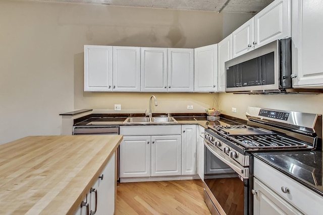 kitchen featuring stainless steel appliances, white cabinetry, sink, and wooden counters