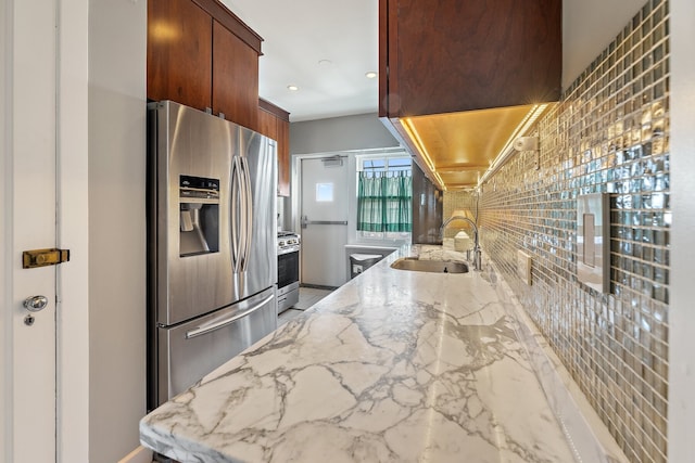 kitchen featuring appliances with stainless steel finishes, sink, and light stone counters