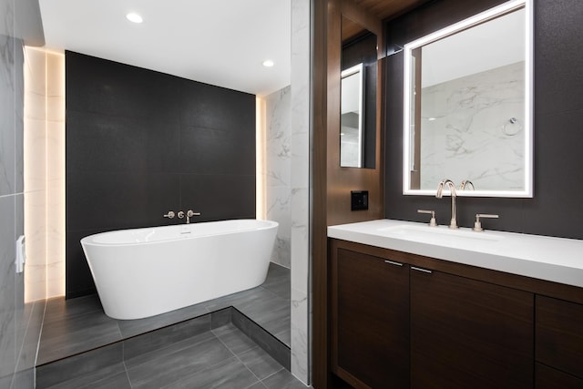 bathroom featuring vanity, a bathtub, and tile walls