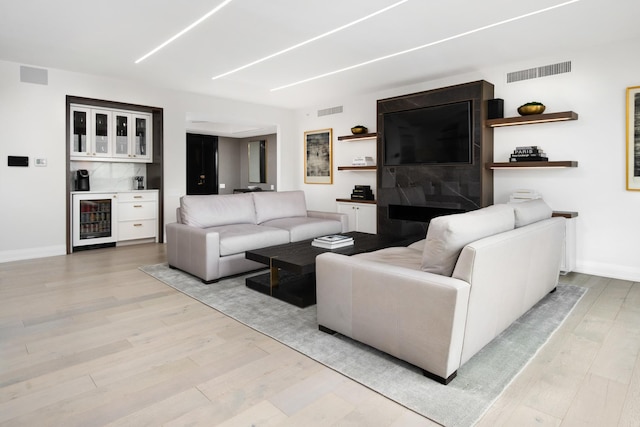 living room featuring wine cooler, bar, and light wood-type flooring