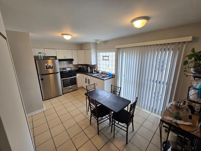 kitchen with backsplash, appliances with stainless steel finishes, light tile patterned floors, and white cabinets