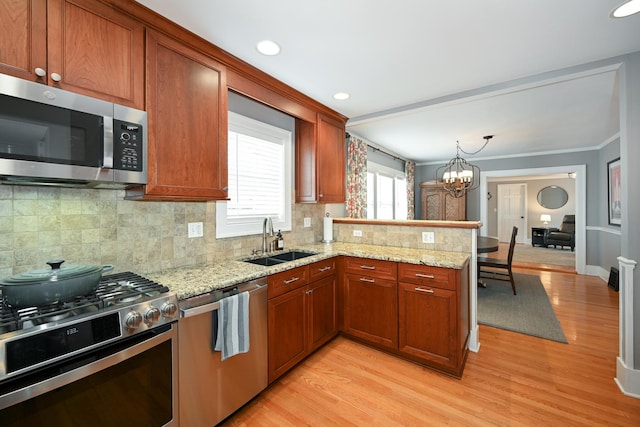 kitchen with sink, an inviting chandelier, light hardwood / wood-style flooring, kitchen peninsula, and stainless steel appliances