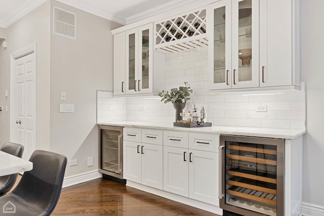 bar with wine cooler, crown molding, light stone countertops, and white cabinets