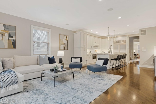 living room with hardwood / wood-style flooring, ornamental molding, and sink