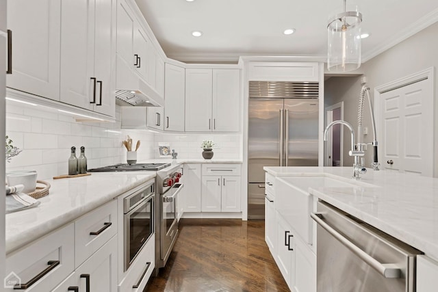 kitchen with pendant lighting, ornamental molding, stainless steel appliances, and white cabinets