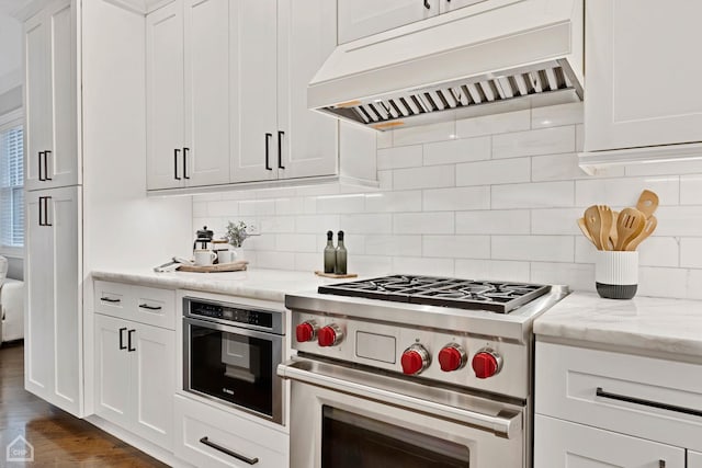 kitchen with premium range hood, stainless steel appliances, light stone countertops, and white cabinets