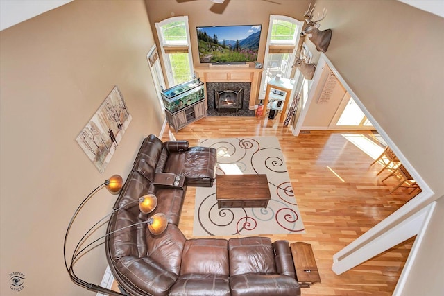 living room featuring ceiling fan, a high end fireplace, and wood-type flooring