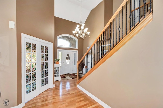 foyer entrance featuring hardwood / wood-style flooring, high vaulted ceiling, and a chandelier