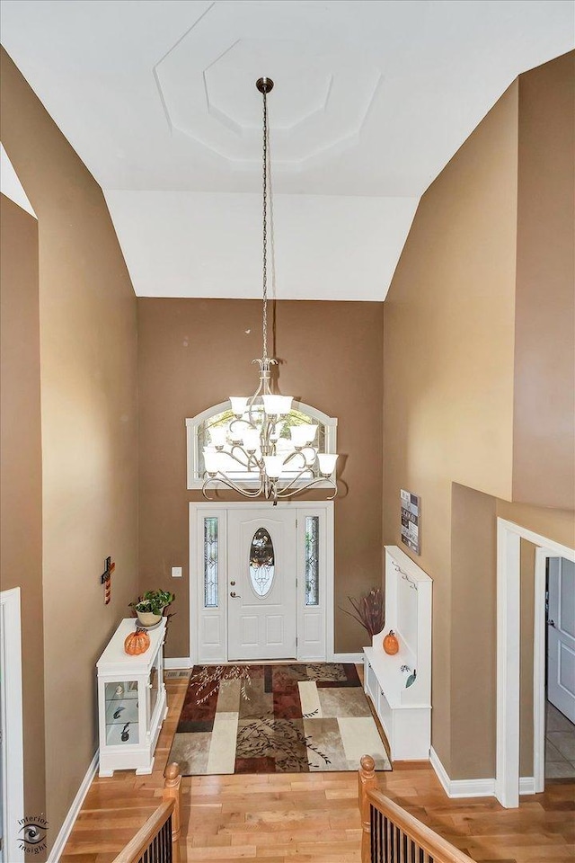 foyer with an inviting chandelier, hardwood / wood-style floors, and high vaulted ceiling