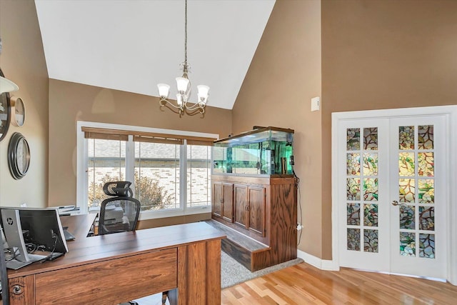 home office with french doors, high vaulted ceiling, an inviting chandelier, and light hardwood / wood-style flooring