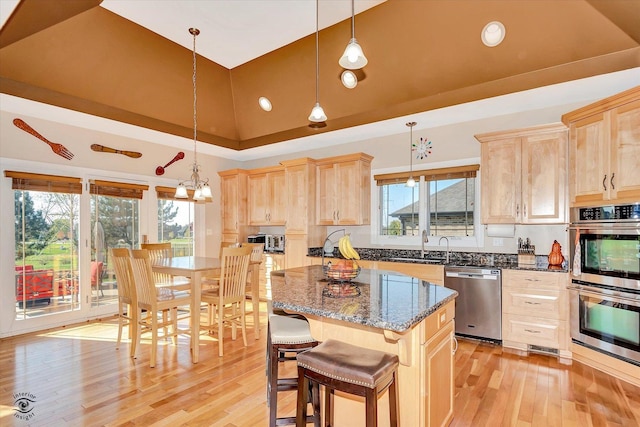 kitchen with stainless steel appliances, a kitchen island, decorative light fixtures, and dark stone counters