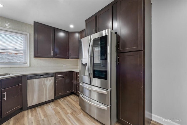 kitchen featuring dark brown cabinetry, appliances with stainless steel finishes, light countertops, and light wood-style floors