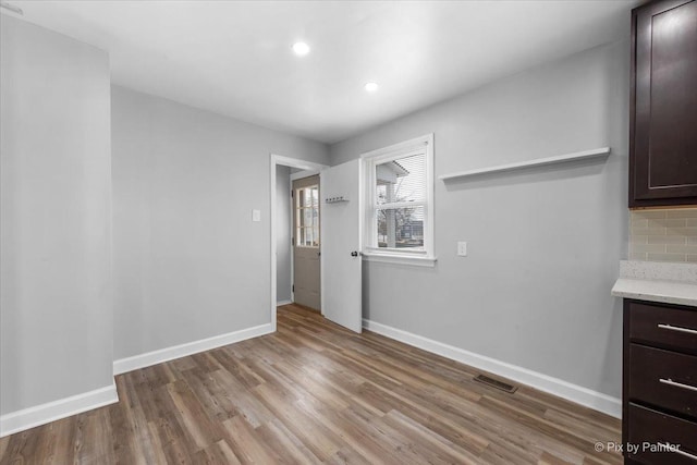 unfurnished dining area with visible vents, baseboards, wood finished floors, and recessed lighting