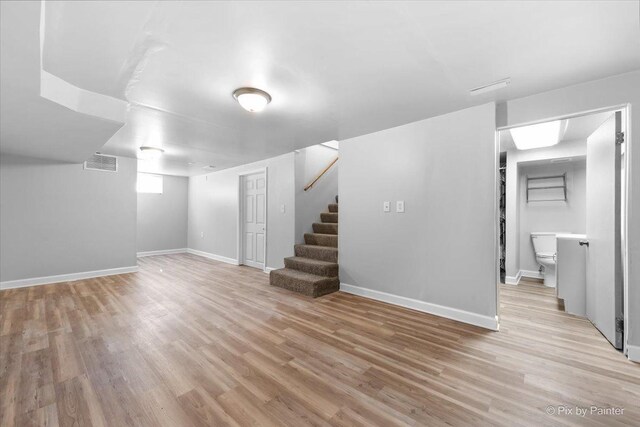 unfurnished bedroom featuring multiple windows, light wood-style flooring, and baseboards