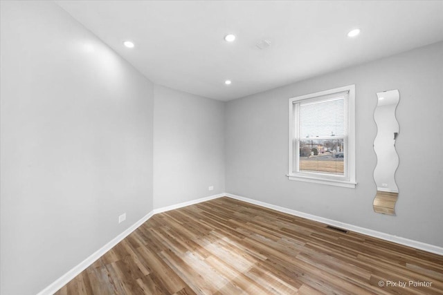 spare room featuring baseboards, visible vents, wood finished floors, and recessed lighting