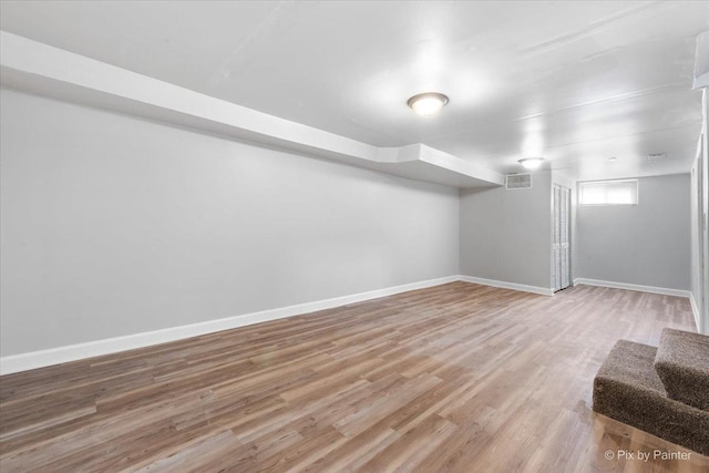 below grade area with visible vents, light wood finished floors, baseboards, and stairs