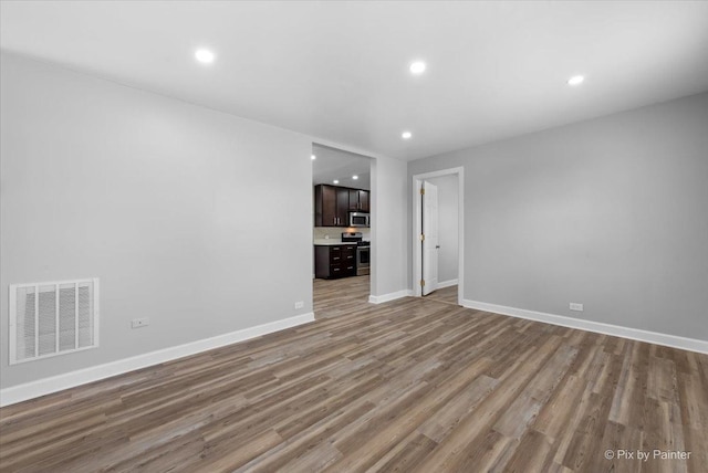 unfurnished room featuring recessed lighting, wood finished floors, visible vents, and baseboards