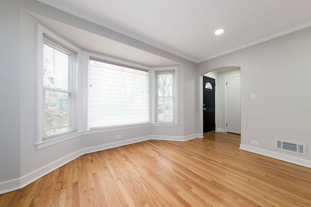 spare room featuring crown molding and light hardwood / wood-style flooring