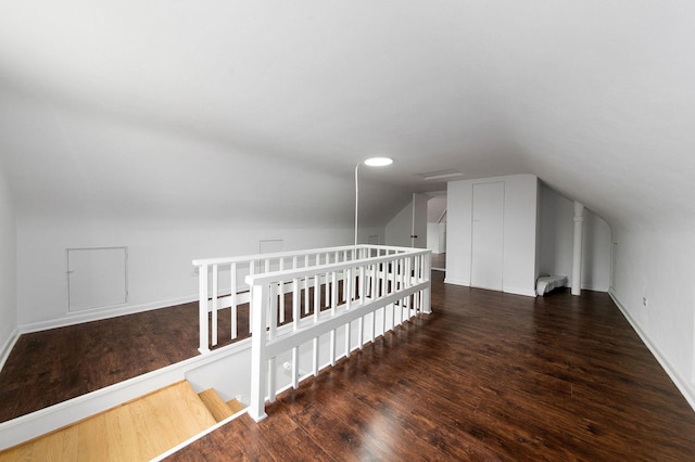 additional living space featuring dark wood-type flooring and vaulted ceiling