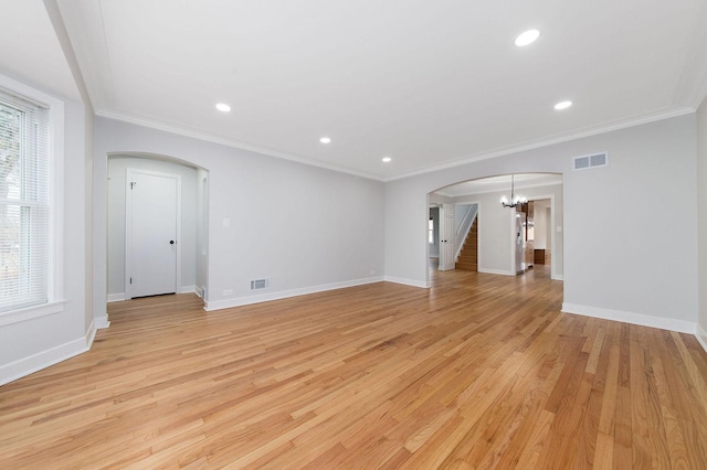 empty room featuring an inviting chandelier, crown molding, and light hardwood / wood-style flooring