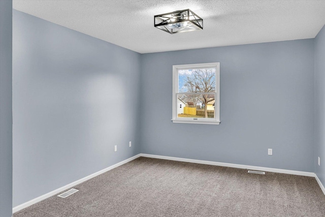 unfurnished room featuring carpet floors, visible vents, baseboards, and a textured ceiling