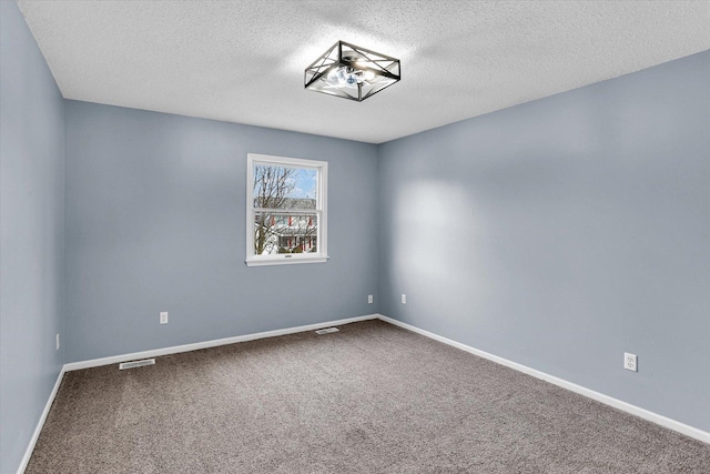 carpeted empty room featuring a textured ceiling, visible vents, and baseboards