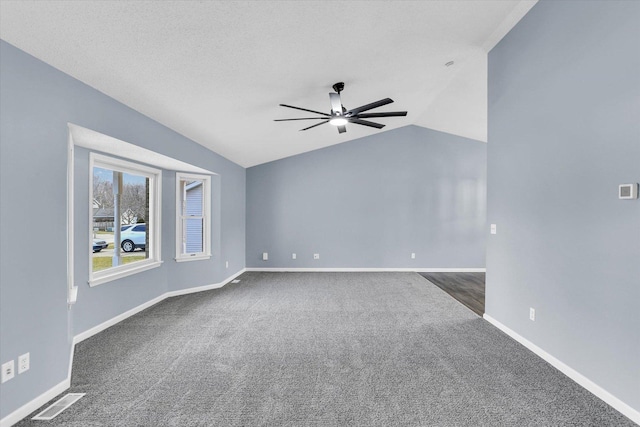 unfurnished room with lofted ceiling, visible vents, dark carpet, ceiling fan, and baseboards