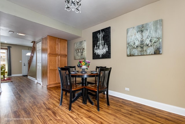 dining room with a chandelier, dark wood-type flooring, and baseboards