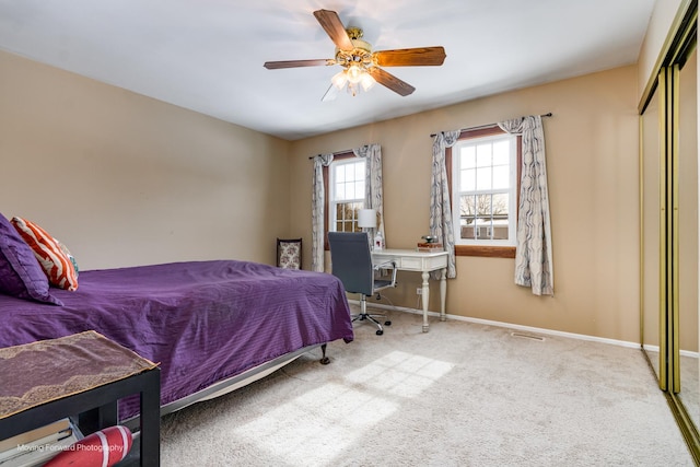 carpeted bedroom featuring a closet, baseboards, visible vents, and ceiling fan