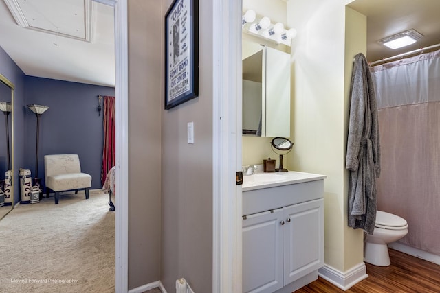 bathroom featuring baseboards, toilet, wood finished floors, and vanity