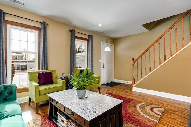 living room with visible vents, a healthy amount of sunlight, stairs, and wood finished floors