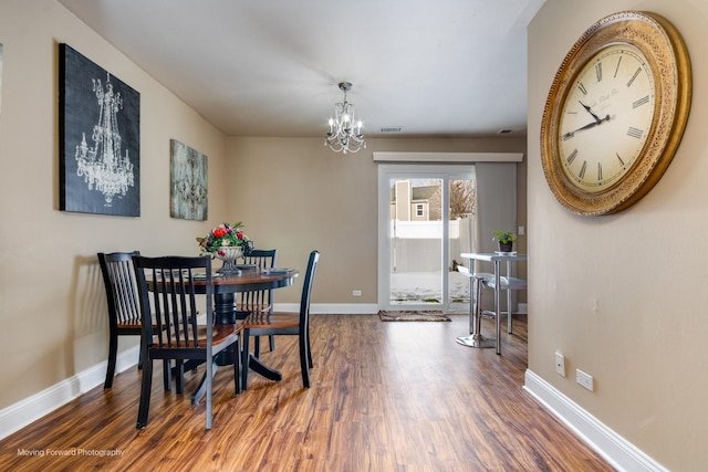 dining room with baseboards, a notable chandelier, and wood finished floors