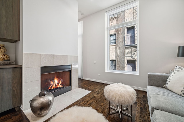 living room with a tiled fireplace and wood-type flooring