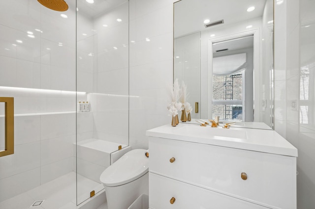 bathroom with tile walls, vanity, toilet, and a tile shower