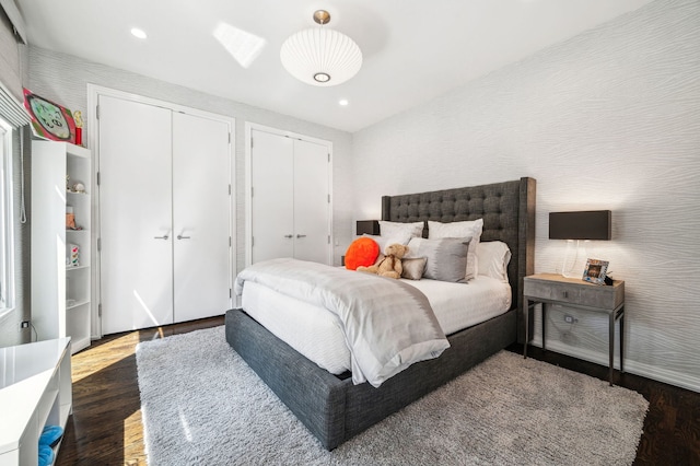 bedroom featuring two closets and dark hardwood / wood-style floors