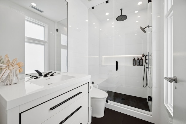 bathroom with a shower with door, vanity, and toilet