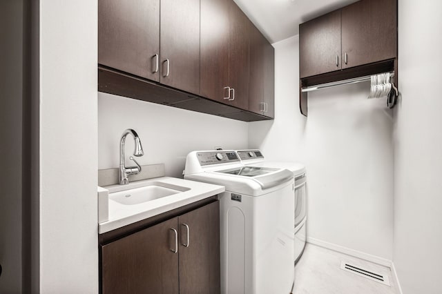 laundry area featuring sink, washing machine and dryer, and cabinets