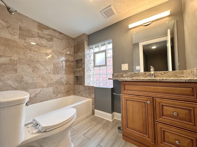 full bathroom with vanity, tiled shower / bath combo, wood-type flooring, and toilet