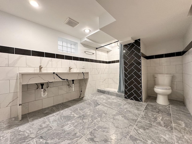 bathroom with walk in shower, toilet, and tile walls